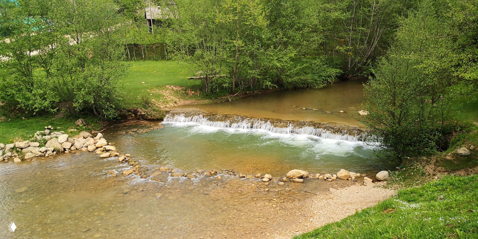 Туристка присела на шпалы узкоколейки среди буйной весенней растительности: тропа и рельсы ведут дальше в лес ущелья.