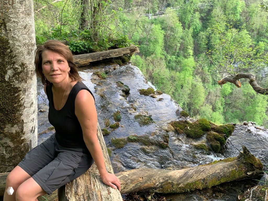 Фотография вида с орлиной полки: отвесный склон, изрезанные скалы и широкий лесной каньон с извивающейся рекой внизу.