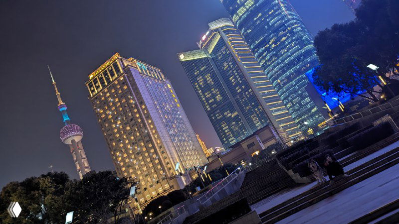 Ночной кадр с видимыми современными башнями и подсвеченными фасадами в деловом квартале, архитектурная иллюминация и городская атмосфера ночью.