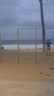 Пустой пляж с тренажёрной конструкцией и пасмурным небом; кадр отражает расслабленную атмосферу и меланхоличный пляжный пейзаж.