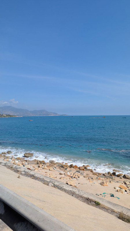 Побережье с бирюзовой водой и каменистым берегом под ясным небом, кадр передаёт пляжную атмосферу и доступ к морю рядом с городом.