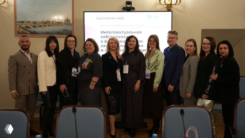 Групповое фото участников круглого стола и организаторов на фоне экрана с названием сессии «Интеллектуальная собственность», люди стоят в зале заседаний.