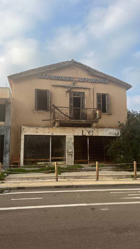 Заброшенный фасад в Вароше: старое здание с балконом и закрытыми витринами, мрачная атмосфера квартала-призрака Фамагусты и улиц 1974 года.