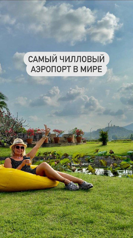 Человек лёжа на жёлтом пуфе на газоне аэропорта Самуи, на заднем плане видна взлётно-посадочная полоса и облачное небо — атмосфера отдыха прямо у самолётов.