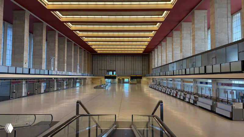 Просторный главный зал регистрации в Темпельхофе с высокими потолками, длинными рядами стоек и ретро-подсветкой в стиле 30-х годов.