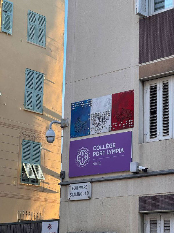 Городской дом в Ницце с вывеской Collège Port Lympia и французским флагом на стене — повседневная урбанистика города.