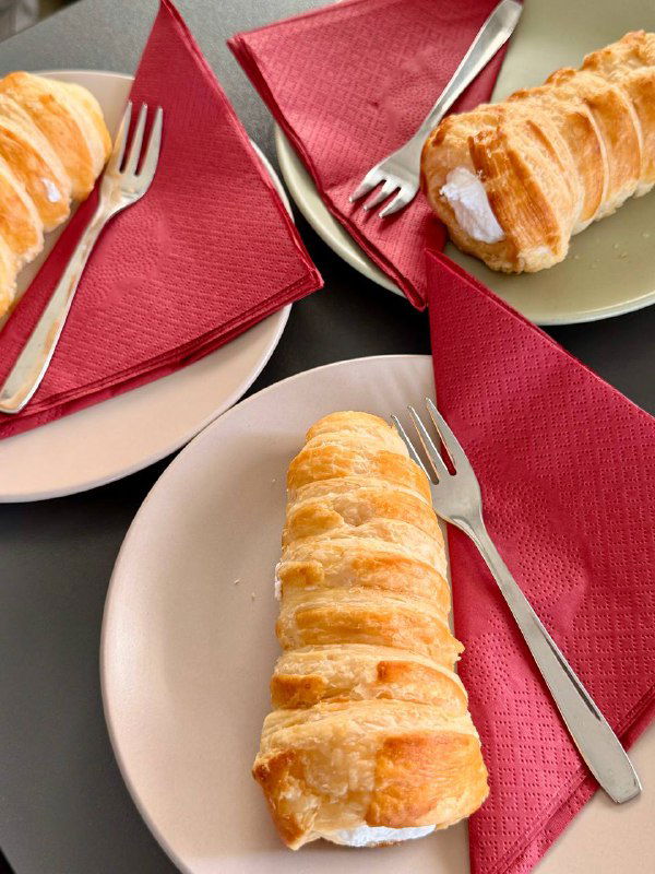 Крупный план трёх тарелок с трубочками и маленькими вилочками на ярко-красных салфетках — детали десертов в придорожном кафе.