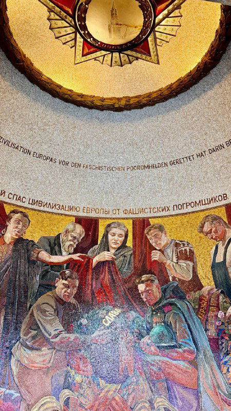 Интерьерная часть мемориального сооружения с росписью и орнаментом в куполе, изображающая людей и памятные тексты на стенах зала.