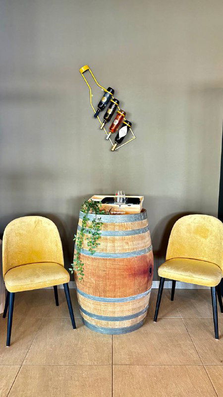 Интерьер винного бутика: винная бочка, стулья и настенная композиция с бутылками — уютная зона для покупателей и гостей.