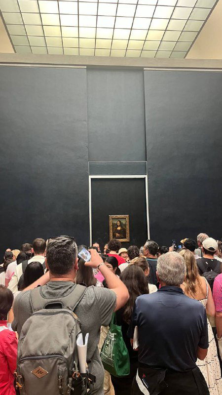 Толпа и очередь перед картиной Мона Лиза в Лувре: множество людей фотографируют маленькое полотно в затемнённом выставочном пространстве