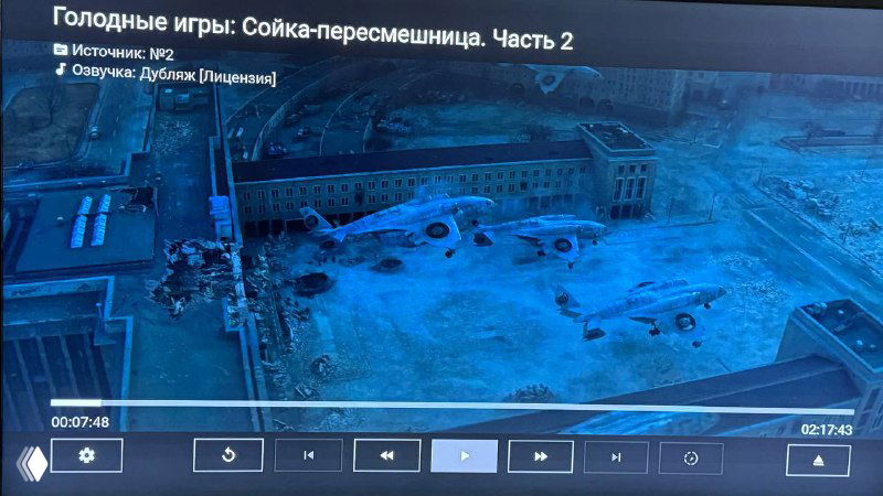 Кадр из фильма: панорамная сцена разрушенного аэропорта с покинутыми самолетами и заснеженной, синим фильтром, пустынной территорией перед терминалом.