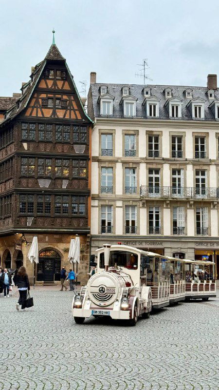 Исторические дома и туристический поезд на площади Страсбурга: вид на городской центр с традиционной архитектурой.