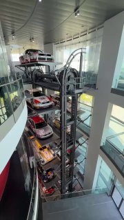 Вертикальный механизм подъёма автомобилей в музее Audi, где несколько машин расположены одна над другой в прозрачной шахте, видно инженерное решение экспозиции.