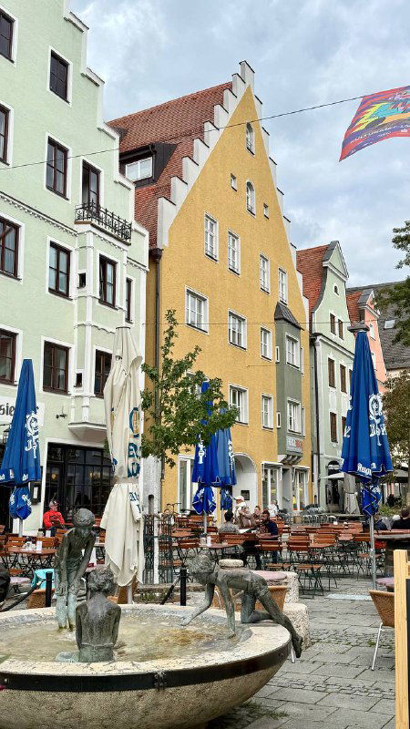 Площадь старого города в Ингольштадте с цветными фасадами зданий, открытыми верандами кафе и фонтаном на переднем плане — типичная баварская атмосфера.