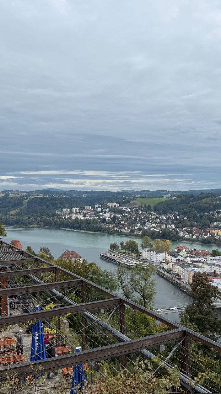 Панорамный вид с холма на излучину рек и пригород Пассау: извилистые берега, зелёные участки и разноцветная застройка вдоль воды.