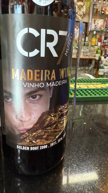 Крупный план бутылки вина с логотипом CR7 и частичным портретом, этикетка бутылки Madeira Vinho Madeira видна крупно.