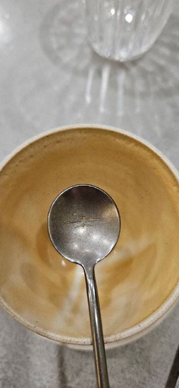 Пустая чашка вблизи с ложкой внутри, акцент на сервировке и деталях посуды в кофейне ЧерникаКофе.