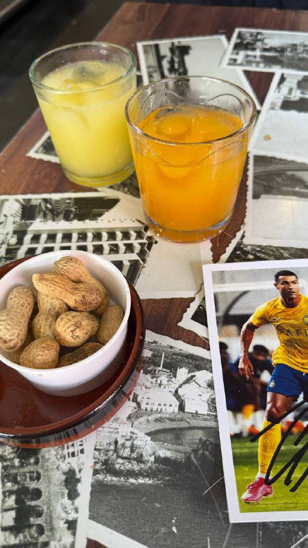 Стол с двумя стаканами местных напитков — понча и никита — и миской с орешками, видна стопка карточек с фото футболистов.