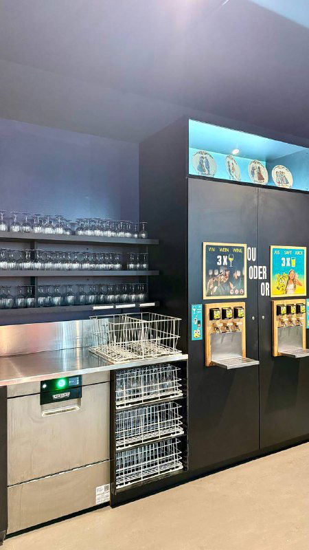 Зона дегустации self-service с автоматами наливания и стойкой для фужеров: три станции наливания, мойка и инвентарь на заднем плане.