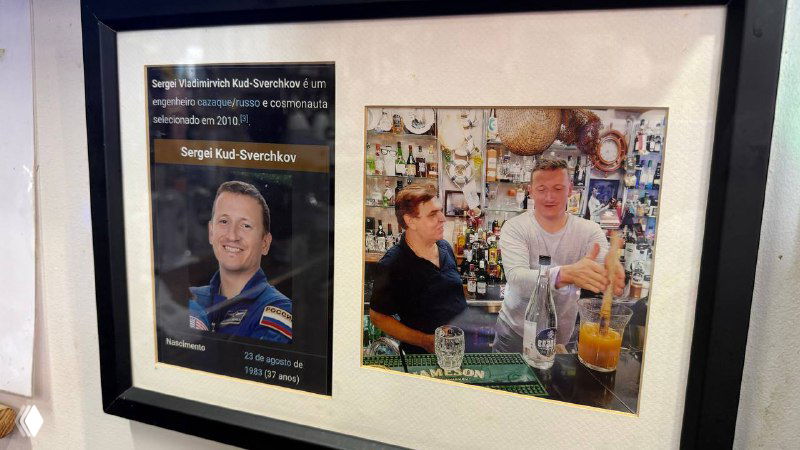 Фотография в рамке на стене бара: местные посетители и снимки, демонстрирующие гостей и атмосферу заведения.