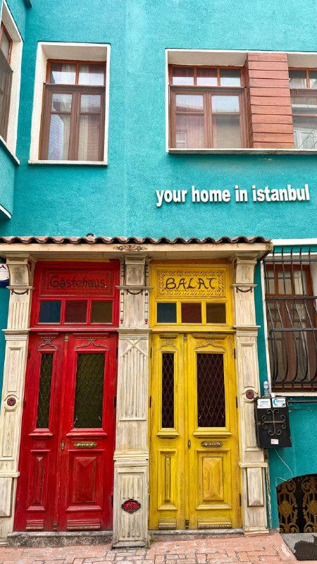 Фрагмент яркого фасада с двумя разноцветными дверями — атмосферный пример цветных жилых домов Балата и туристических фото-локаций.