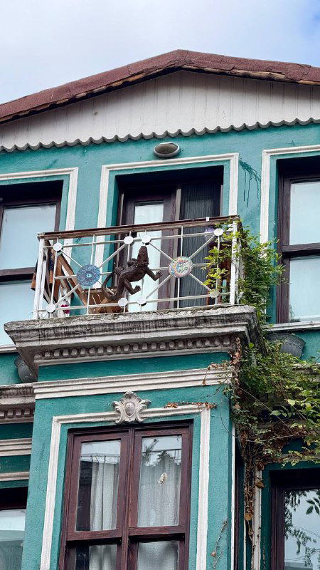 Балкон и фасад бирюзового дома с декоративными элементами; пример деталей, которые автор советует внимательно рассматривать во время прогулки.