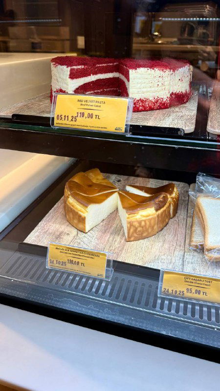 Витрина с кусочками чизкейка Сан Себастьян и другими десертами в McDonald's; ценники и яркая подсветка