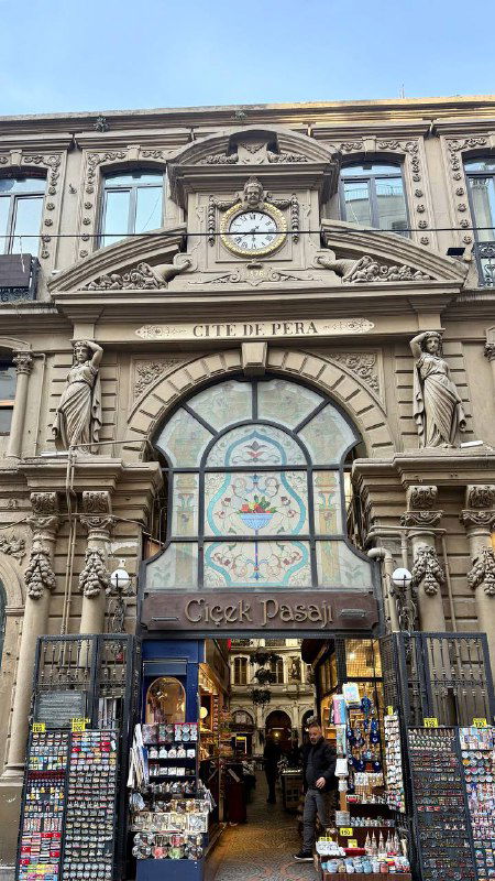 Фасад и вход в Цветочный пассаж (Çiçek Pasajı) с арочным витражом и проходом в украшенное помещение с витринами и посетителями у входа.