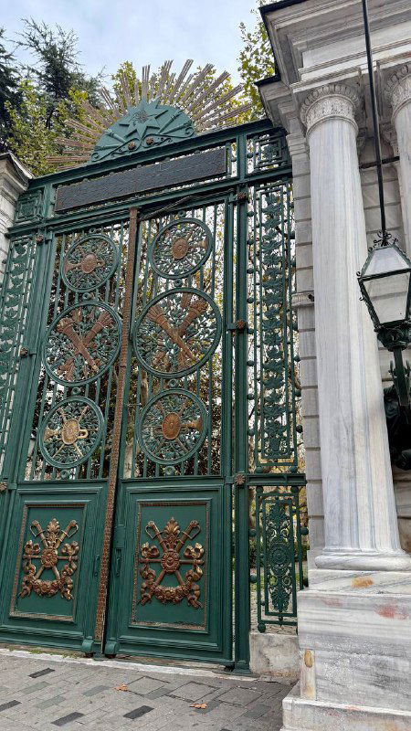 Декоративные зелёные ворота с орнаментом и колоннами у входа в историческое здание рядом с Истикляль, металл и каменная архитектура в кадре.