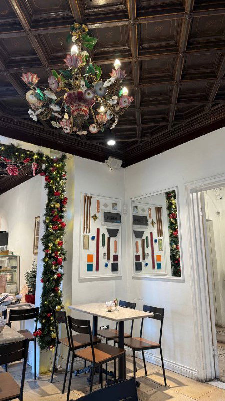 Художественная люстра и интерьер кафе с белыми стенами, картинами и столиками — декоративный и уютный уголок Pera Bakery.