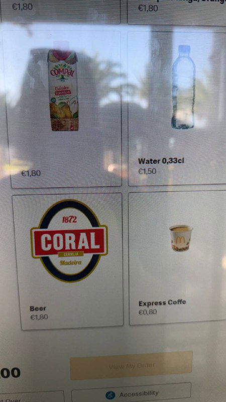 Крупный план части меню с ценами: бутылка воды, пиво и другие позиции в португальском Макдональдсе, видны евро‑цены.