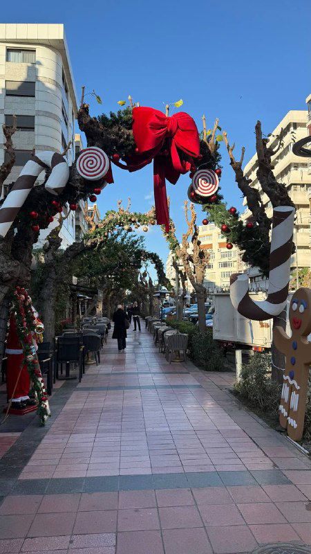 Проход украшен леденцовыми арками и бантиками над тротуаром — праздничные инсталляции тянутся по аллее в Измире, создавая атмосферу сказки.