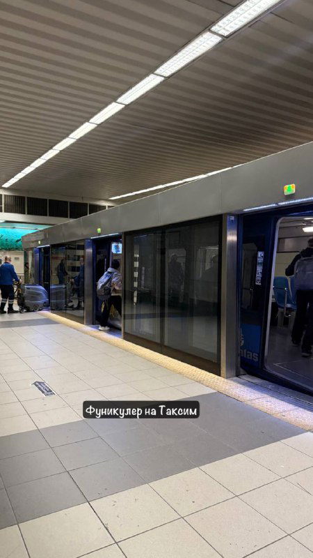 Платформа станции метро или фуникулера в Стамбуле с поездом у перрона, стеклянные двери, пассажиры и освещение станции