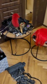 Стол с реквизитом для косплея: картонный тесак в стиле Пирамидхэда, красные парики и элементы костюма разбросаны рядом.