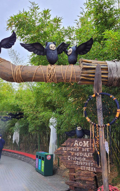 Декоративные вороны на ветке и тематические венки в зелёной зоне парка — композиция в стиле мрачного фольклора и хэллоуина.