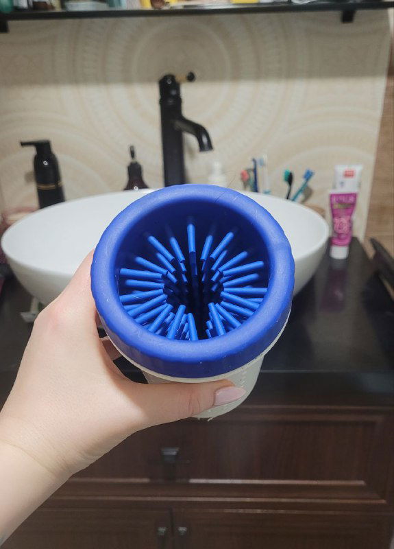 Портативная голубая лапомойка для собак Берта: силиконовый вкладыш с гибкими щетинками, вид сверху на руке у ванной — сравнение с мерчевым ведром.