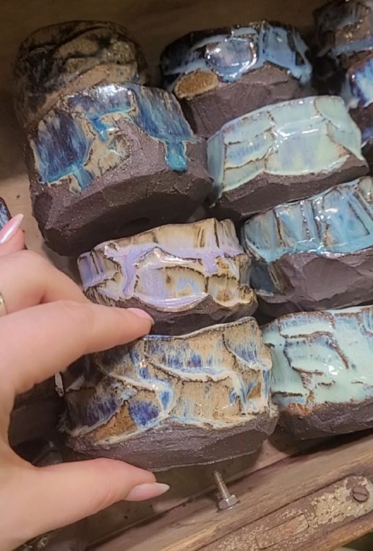 Крупный план керамических чаш и ваз с глазурью: текстуры и оттенки зелёного и коричневого в ассортименте местной мастерской.