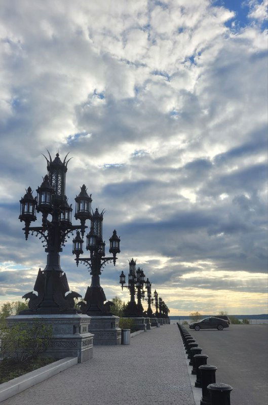 Ряд высоких декоративных фонарей и плоскость набережной у Волги в пасмурный день, перспектива у замка Гарибальди