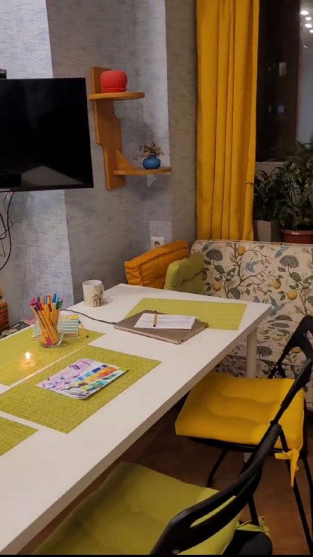 Обеденная зона с большим столом, стульями и декоративными предметами; открытая планировка, цветовые акценты в интерьере.