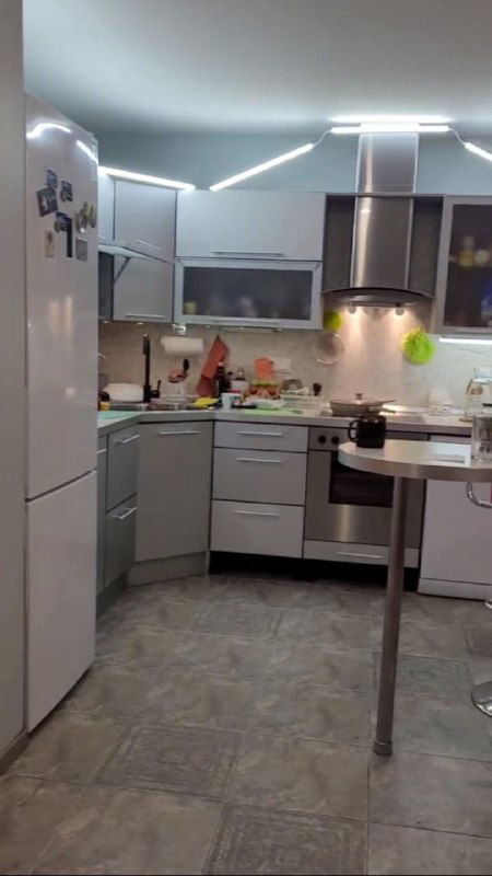 Кухонная зона с белой кухонной мебелью, вытяжкой и барной стойкой — современный и аккуратный кухонный гарнитур.