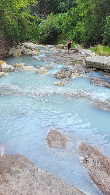 Широкий участок реки с молочно-голубой водой, люди на дальнем плане у берега, естественный пейзаж черноморского побережья у Мацесты