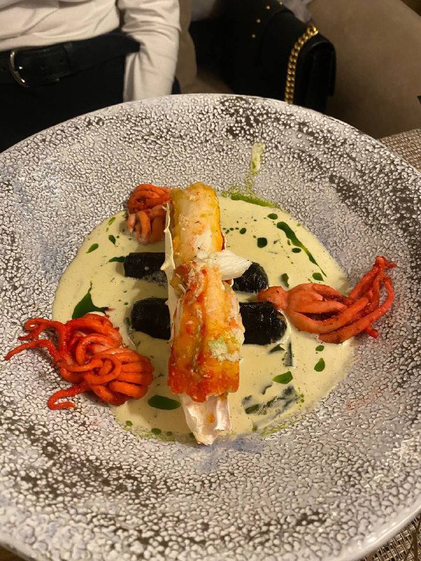 Блюдо с крабом и соусом на декоративной тарелке: аккуратно сервированное морепродуктовое блюдо из ресторана Терраса, отмеченное автором.