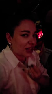 Кадр из видео: крупный план поклонницы в ночном клубе на фоне тёмного зала и красных сценических огней, атмосфера живого концерта.