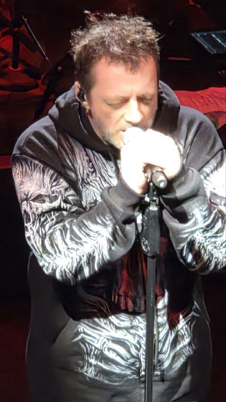 Крупный план Глеба у микрофона во время исполнения, артист сосредоточен, видно эмоции в момент песни и сценическое освещение.