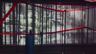 Инсталляция в музейном пространстве: проекция на занавеси и красные ленты/струны в переднем плане, созвучие ритма и швов в экспонате.