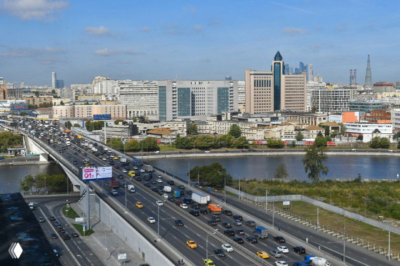 Шоссе и мост через реку с интенсивным движением, вид на деловые кварталы и городскую инфраструктуру Москвы с автомобильным потоком.