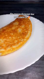 Крупный план золотистого блина на белой тарелке; блин сложен с сырной начинкой и ломтиками помидора; на фото также видна надпись о похудении.