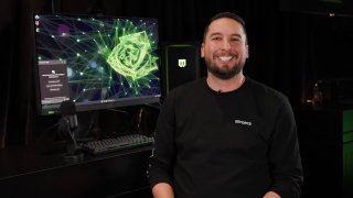 Человек улыбается на фоне монитора с графикой нейросети и зелёными элементами Nvidia, демонстрационное фото продукта.