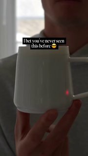 Человек держит белую кружку PixelMug в руке; видна часть лица держателя и маленький световой индикатор на корпусе.