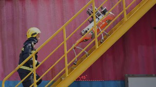 Квадропед Unitree B2 поднимается по металлической лестнице рядом со спасателем в каске; показана проходимость и манёвренность робота в сложной обстановке.